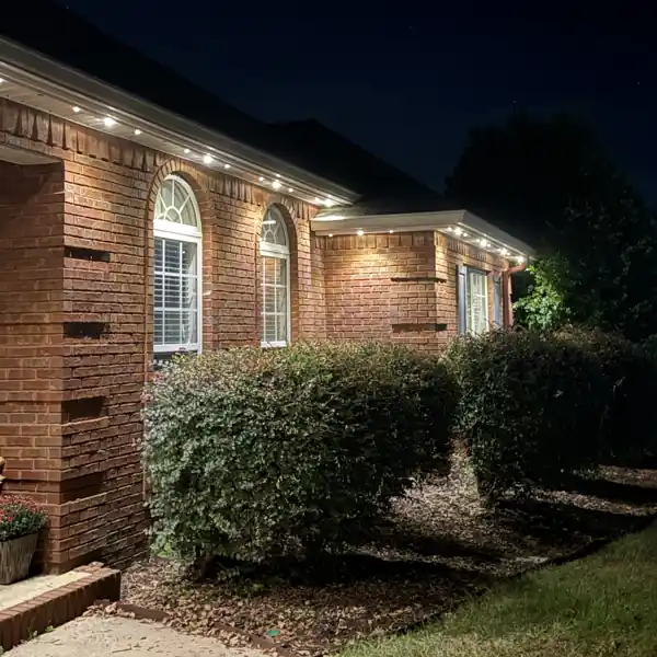 Permanent track lighting running down the side roofline of a brick home