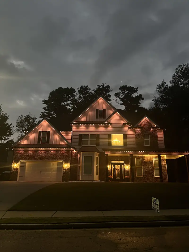 Home with warm white permanent roofline lighting at dusk